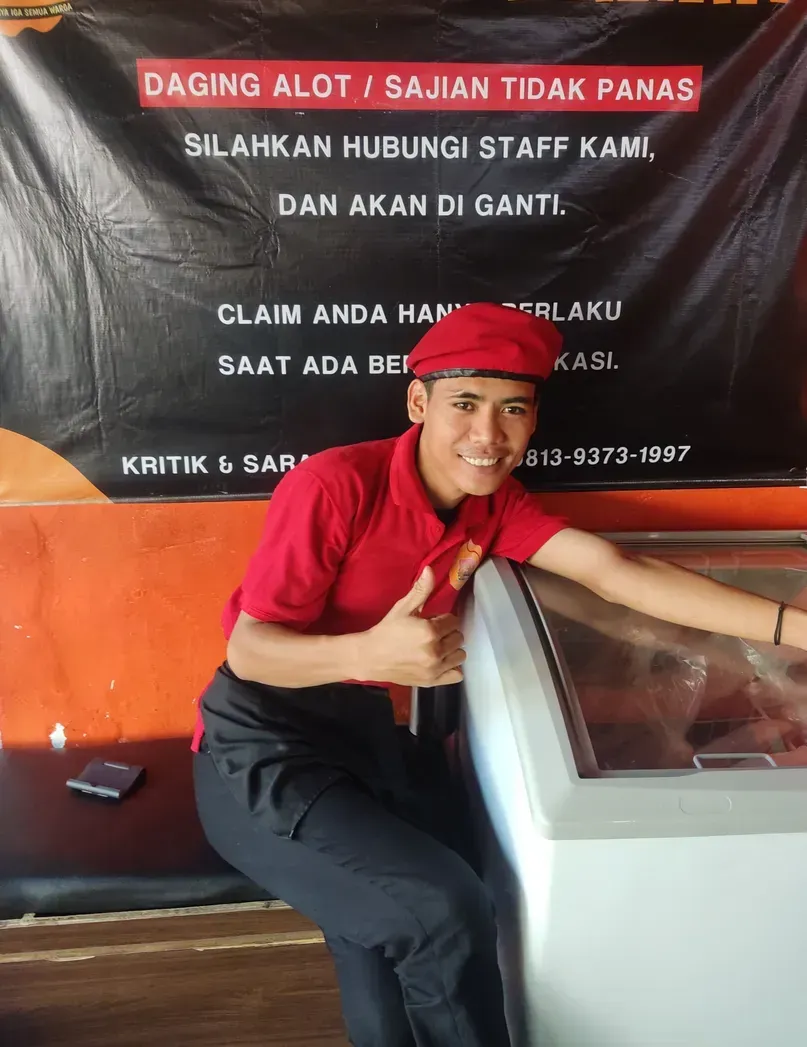 Kru di depan spanduk Garansi Sajian: daging alot atau sajian tidak panas akan diganti